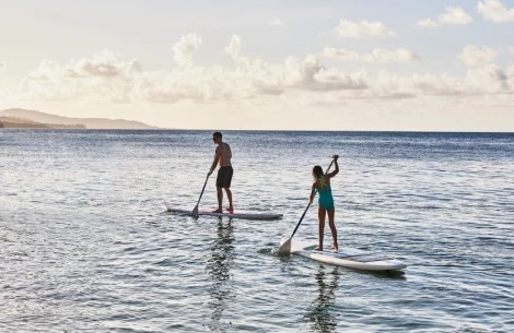 a man and woman on paddle boards in the water