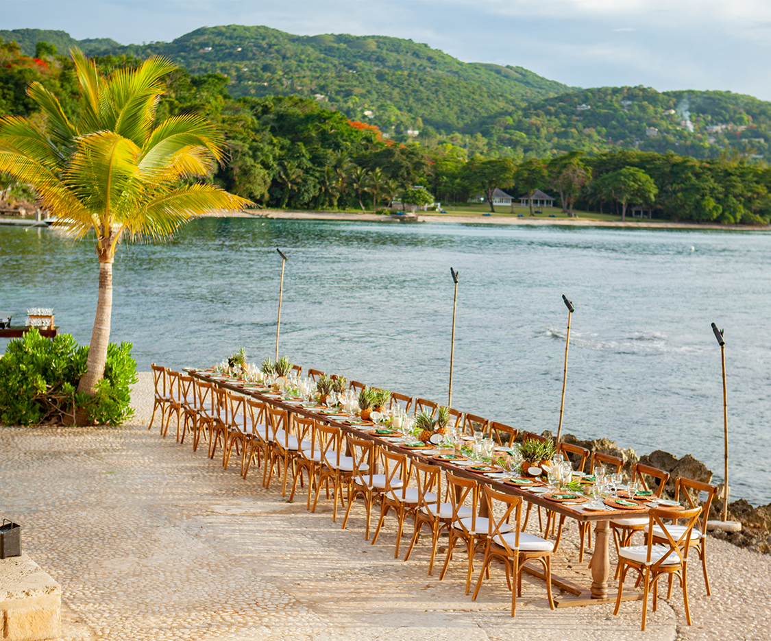 a long table set up with chairs and flowers on it