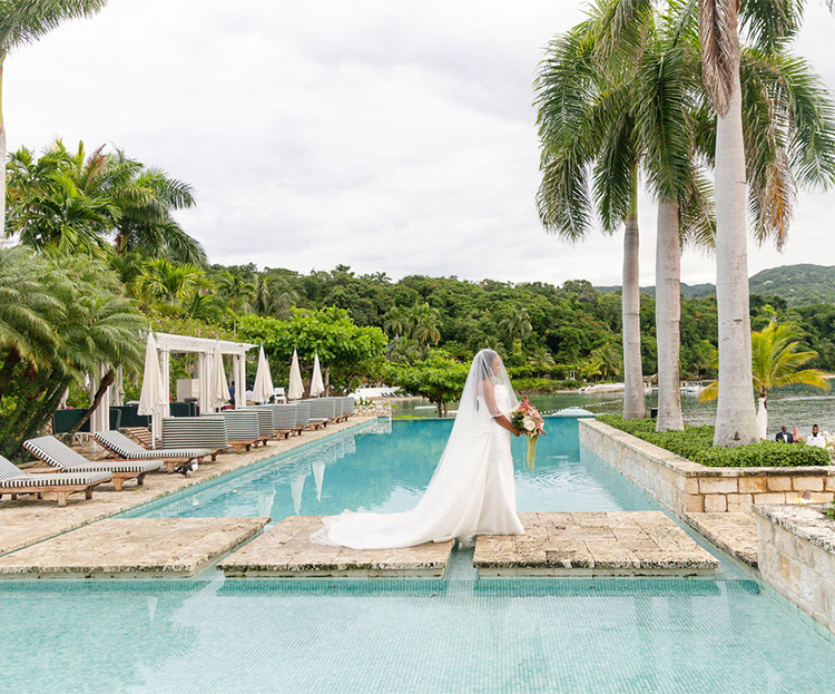 a woman in a white dress holding a bouquet of flowers in a pool