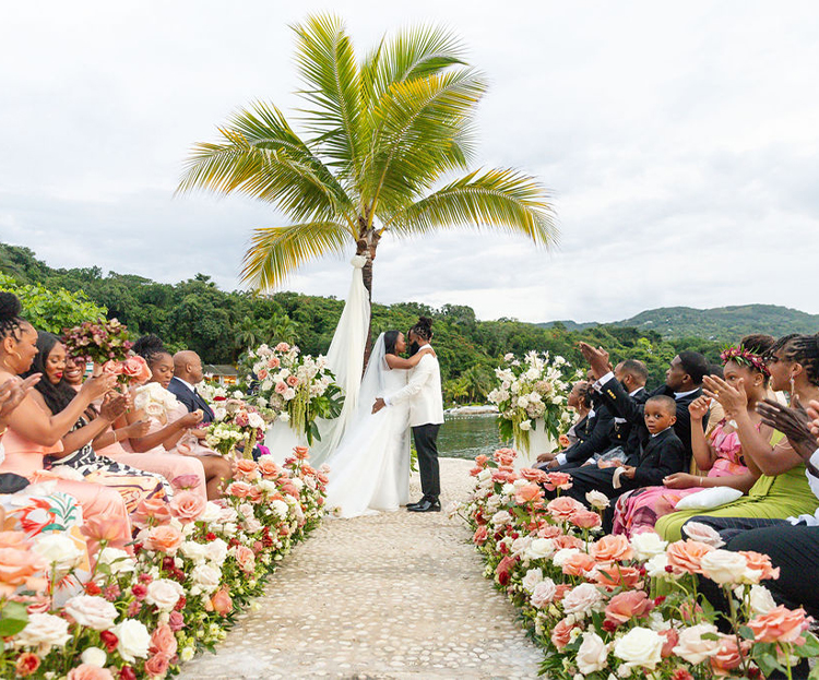a bride and groom kissing under a palm tree