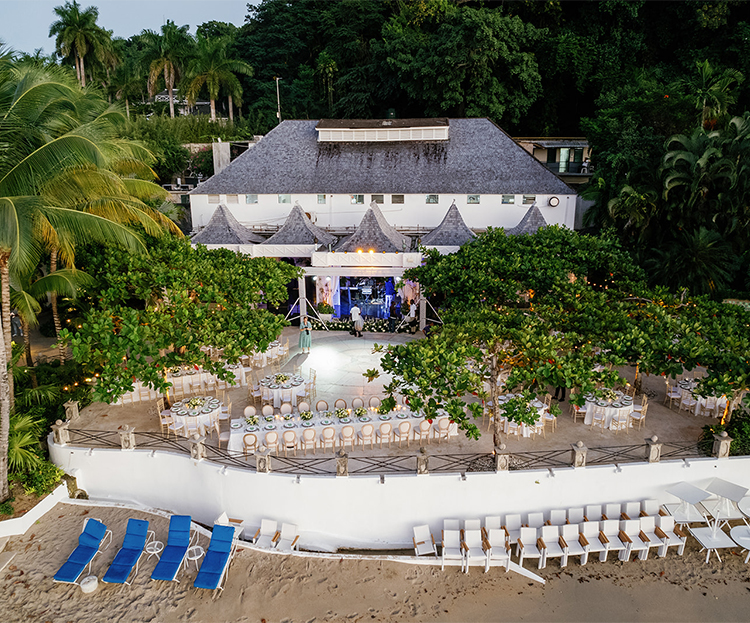 a white building with tables and chairs on the beach