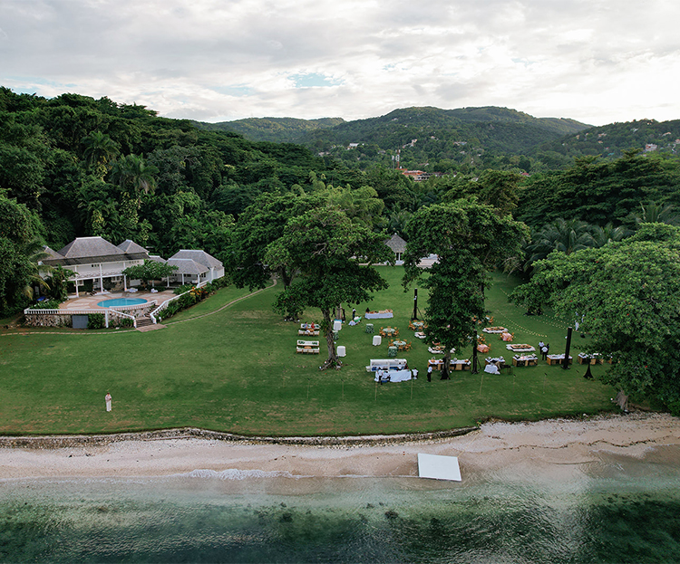 a large lawn with tables and chairs on it by a body of water