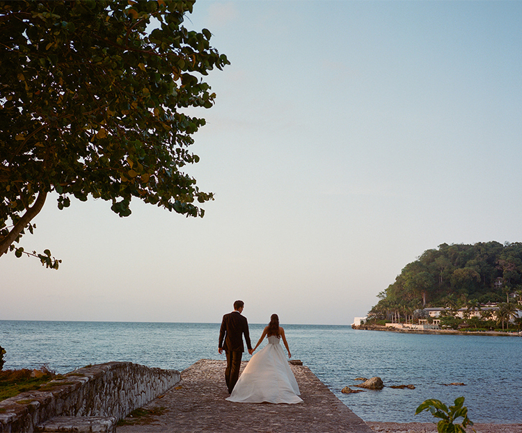a man and woman in wedding dress walking on a dock
