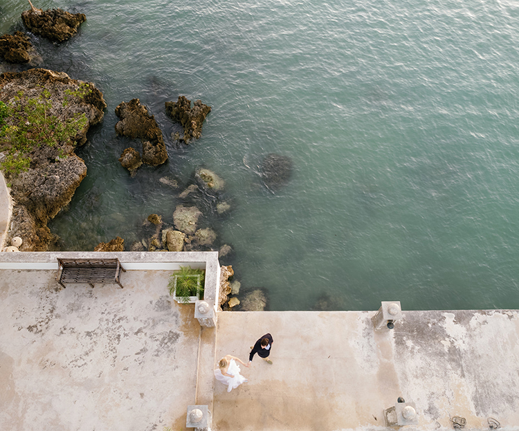 a couple of people standing on a concrete deck overlooking a body of water