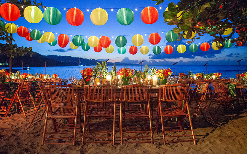 a table set up with colorful lanterns and a beach in the background