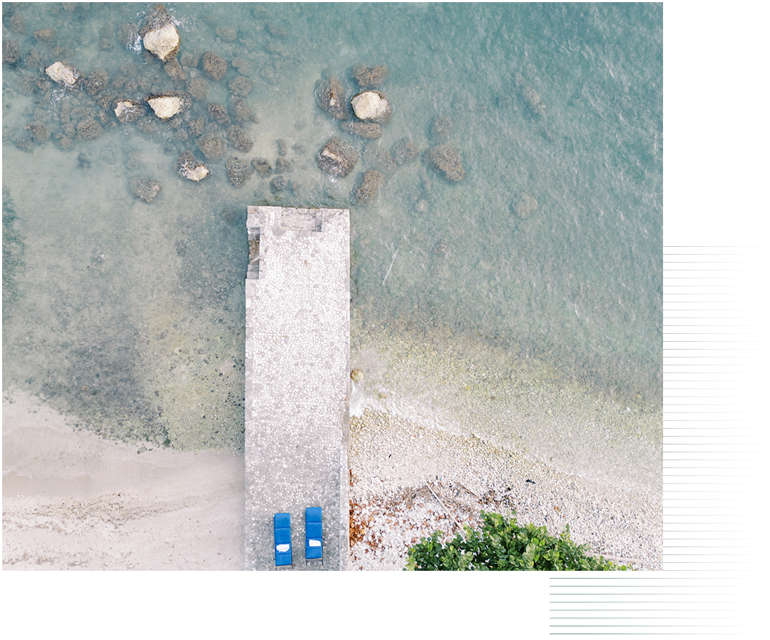 a dock with blue beach chairs on it and rocks in the water