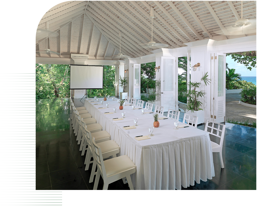 a long table with white tablecloths and chairs in a room with a projector screen
