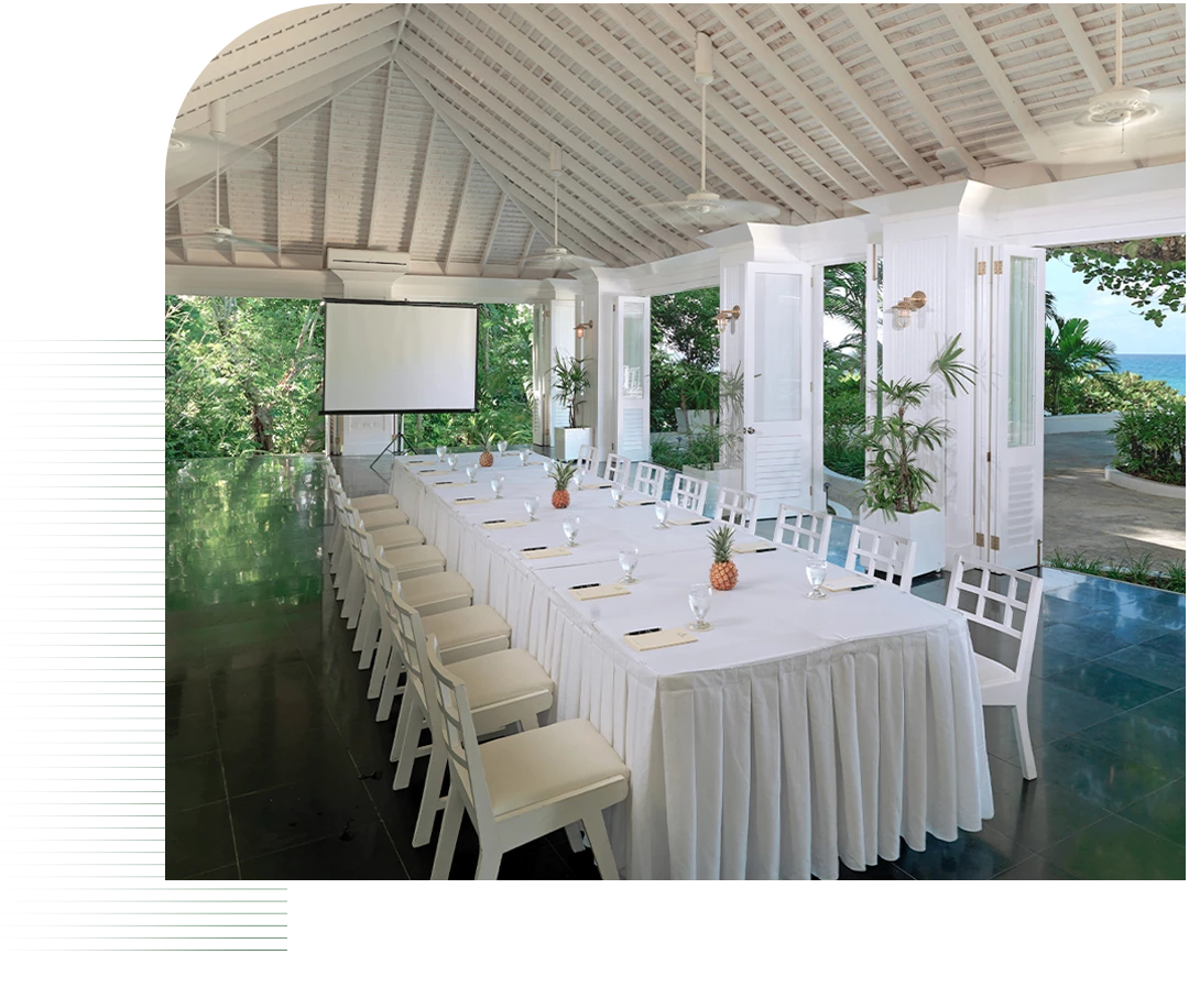 a long table with white tablecloths and chairs in a room with a projector screen