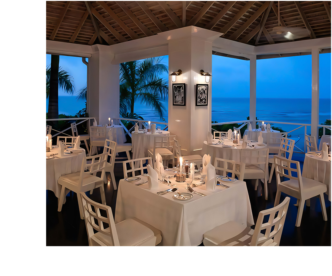 a room with tables and chairs and a view of the ocean
