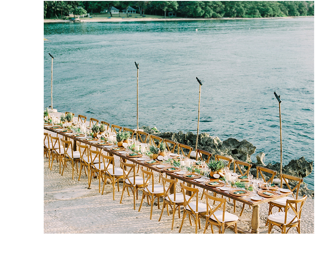 a long table set with chairs and tables on a beach