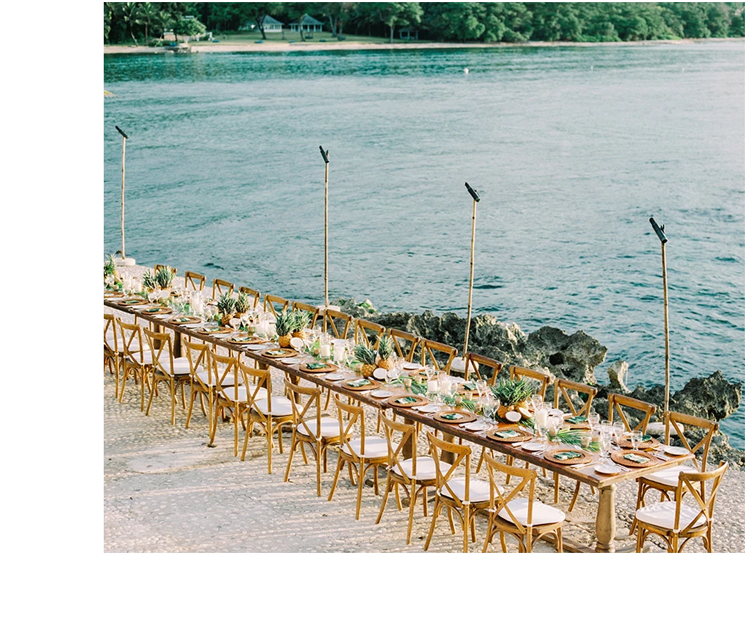 a long table set with chairs and tables on a beach