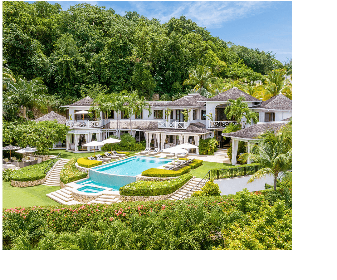 a large white house with a pool surrounded by trees