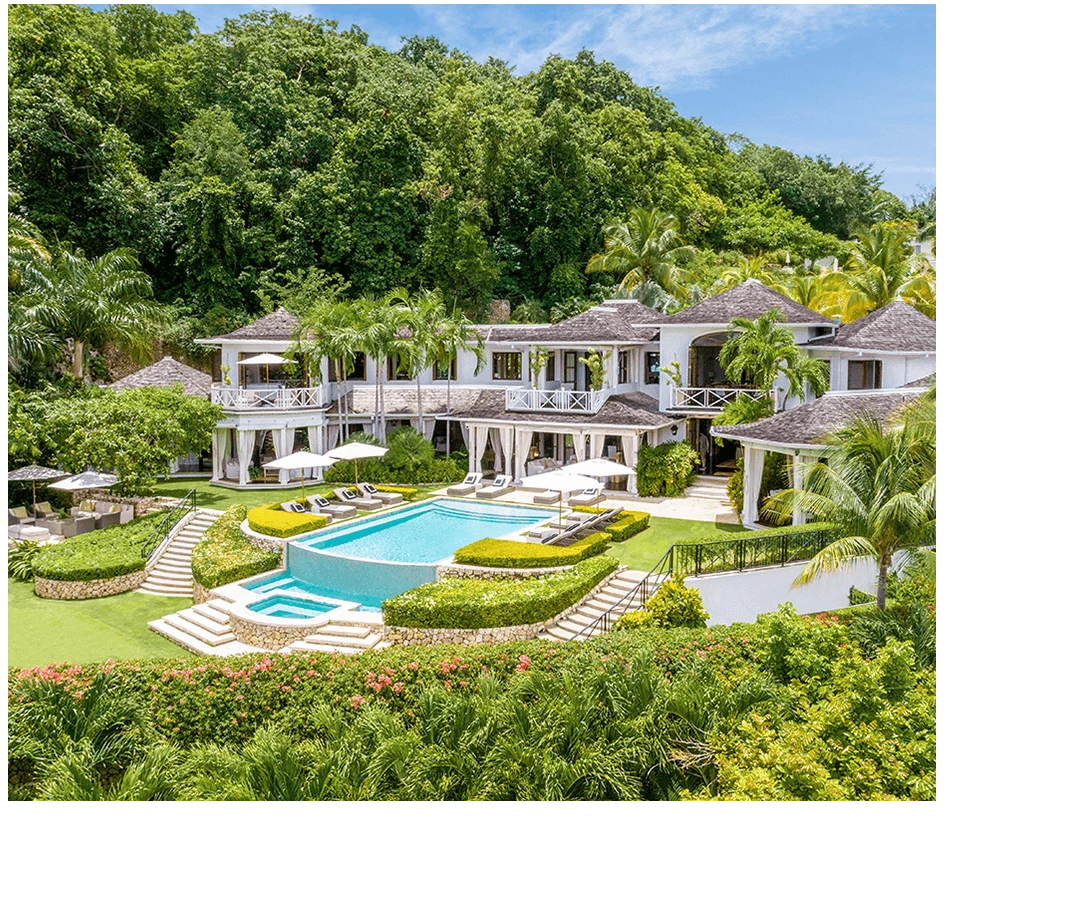 a large white house with a pool surrounded by trees