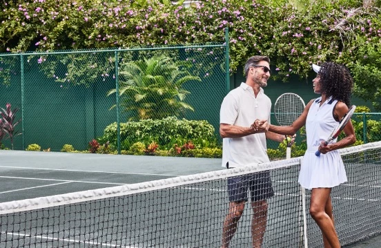 a man and woman shaking hands on a tennis court