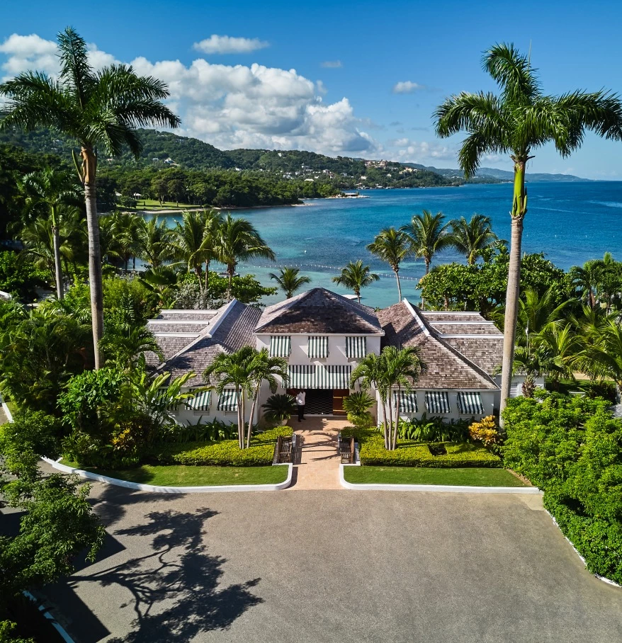 a large house with trees and a body of water