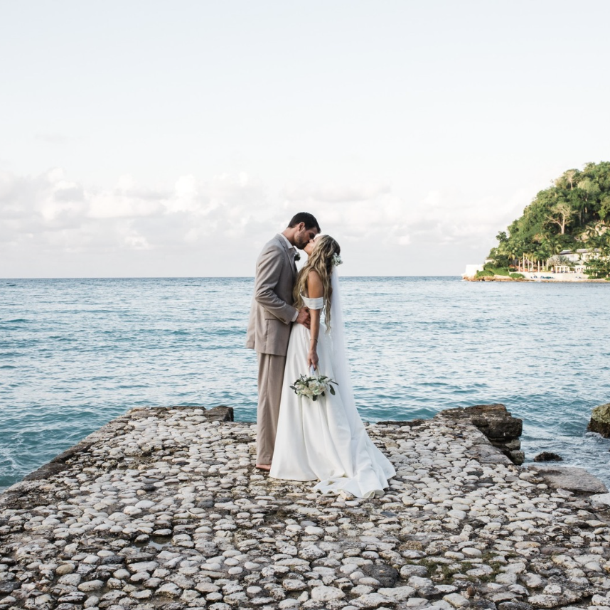 a man and woman kissing on a rock pier