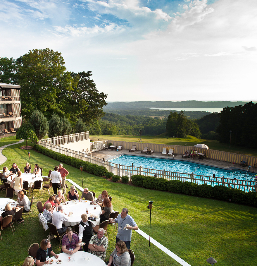 a group of people sitting around tables outside a pool