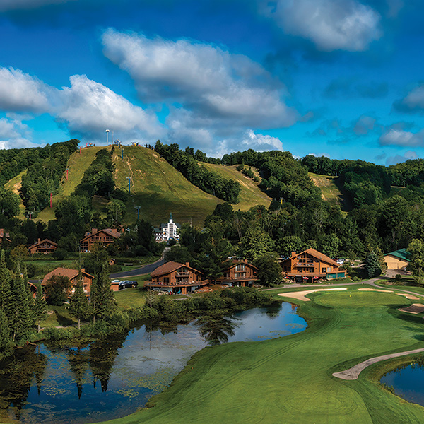 a golf course with a lake and houses on the side