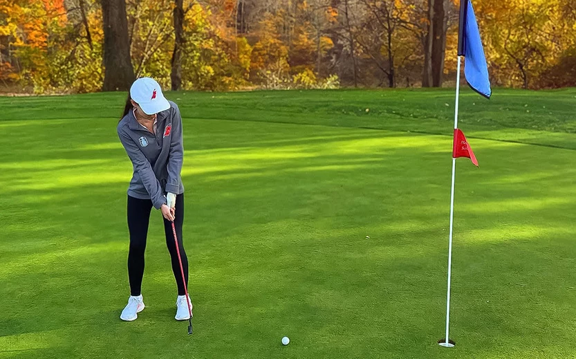 a woman playing golf on a green field