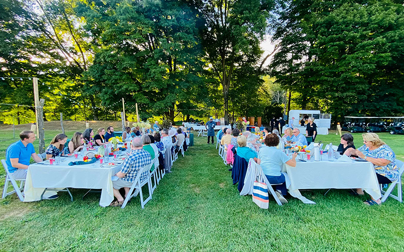 a group of people sitting at tables in a grassy area