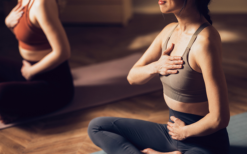 a woman sitting on a yoga mat holding her chest