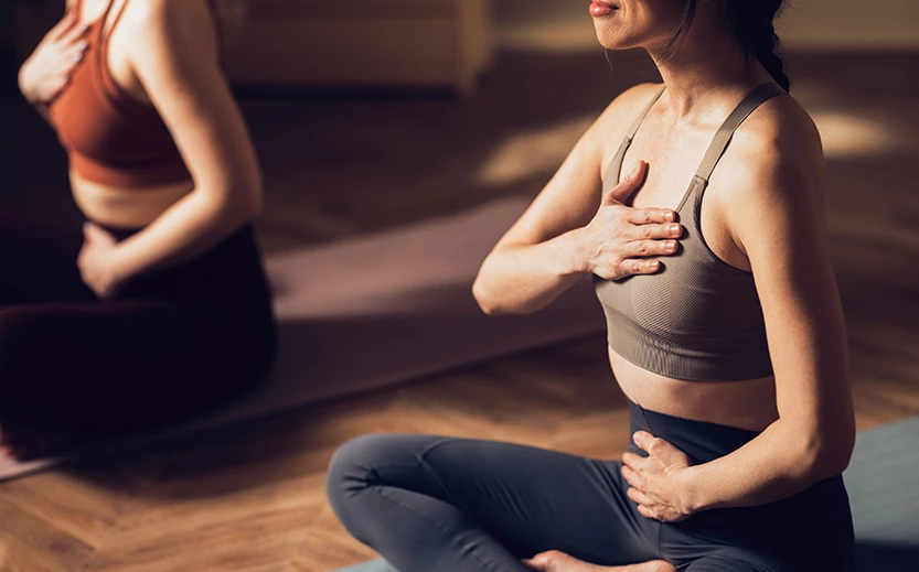 a woman sitting on a yoga mat holding her chest