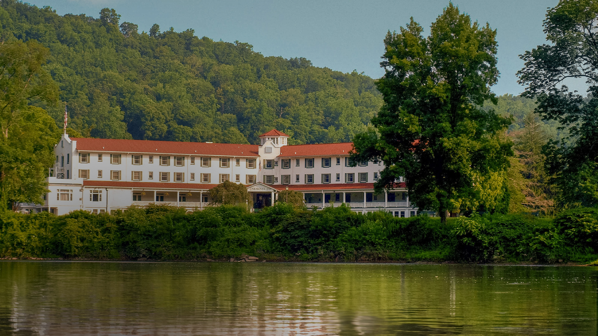 a large white building with red roofs next to a body of water