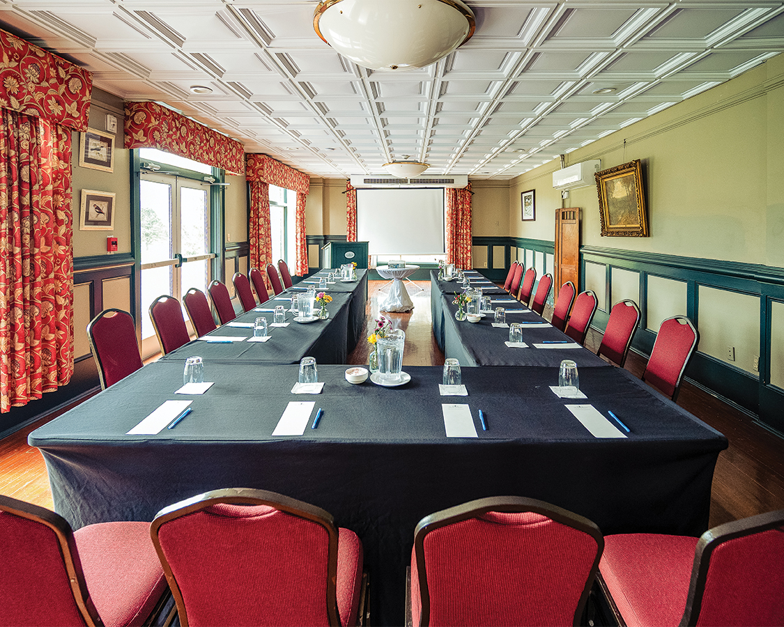 a long conference room with black table cloths and red chairs