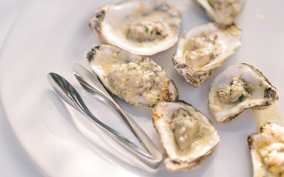 a plate of oysters and tongs