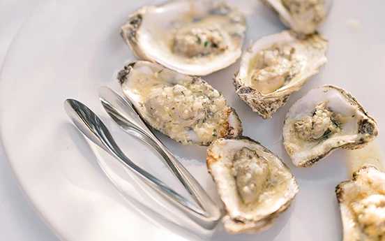 a plate of oysters and tongs