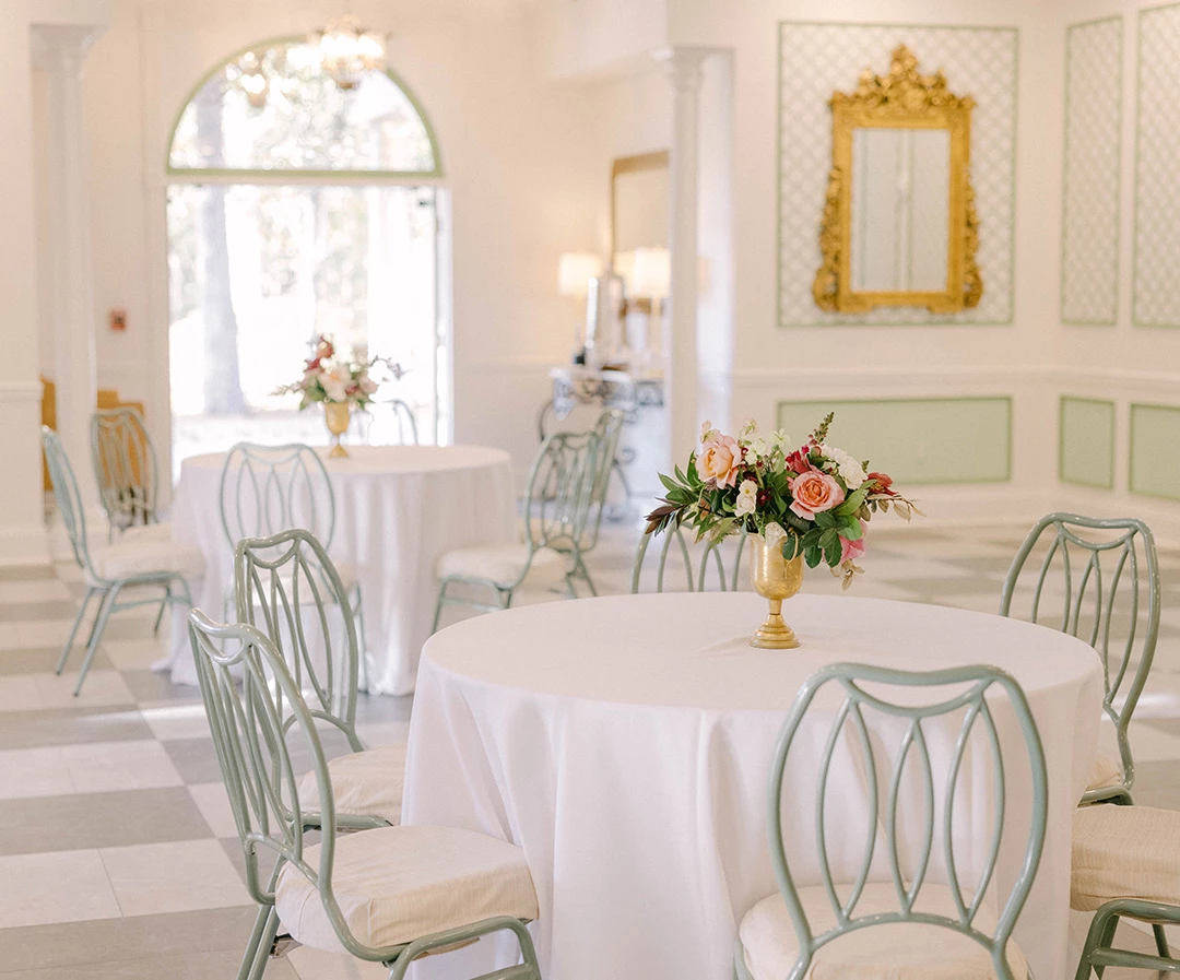 a table set up in a room with white tables and chairs