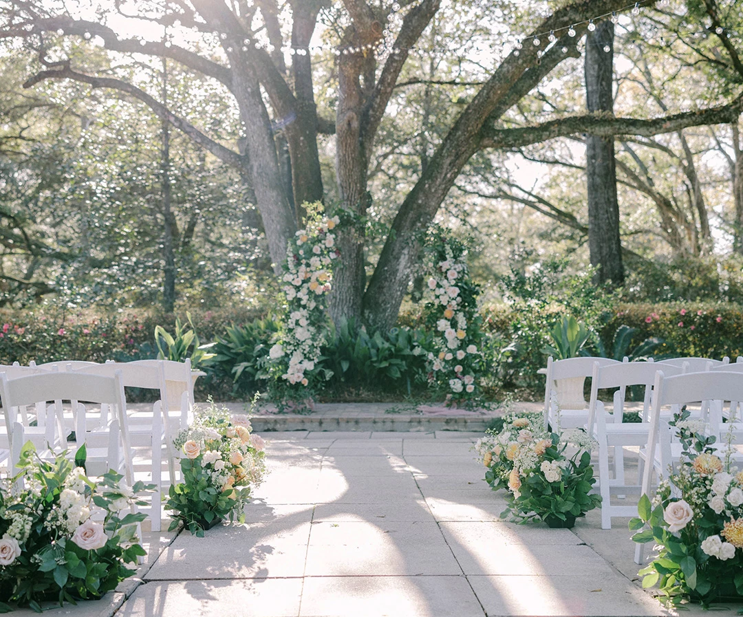 a wedding ceremony with white chairs and flowers