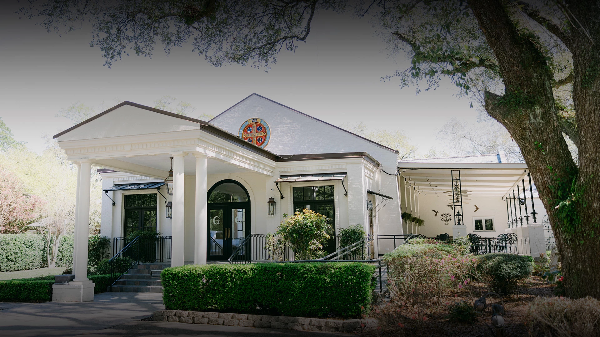 a white building with columns and a red cross on the front