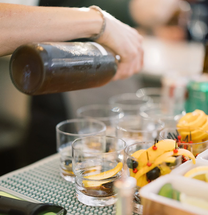 a person pouring a drink into glasses