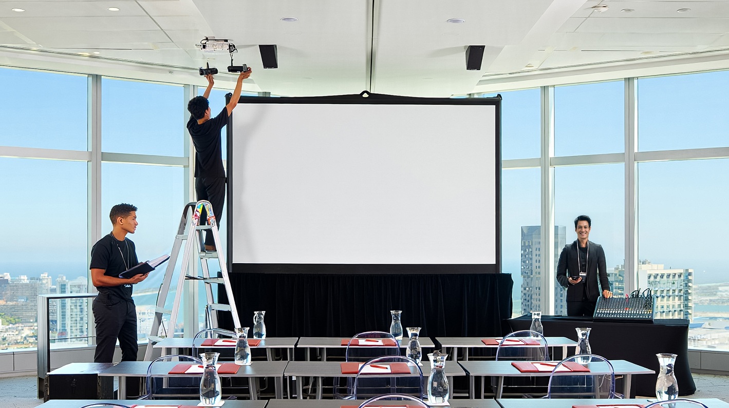 a man on a ladder fixing a projector screen