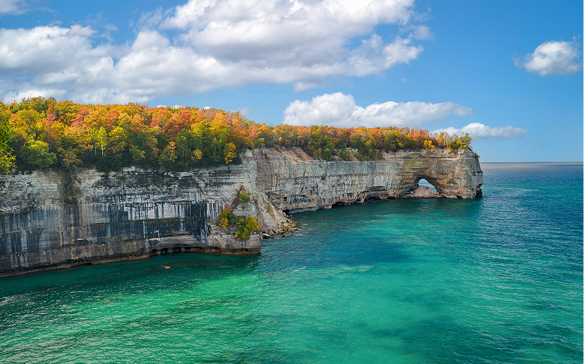 a cliff with trees on it with Pictured Rocks National Lakeshore in the background