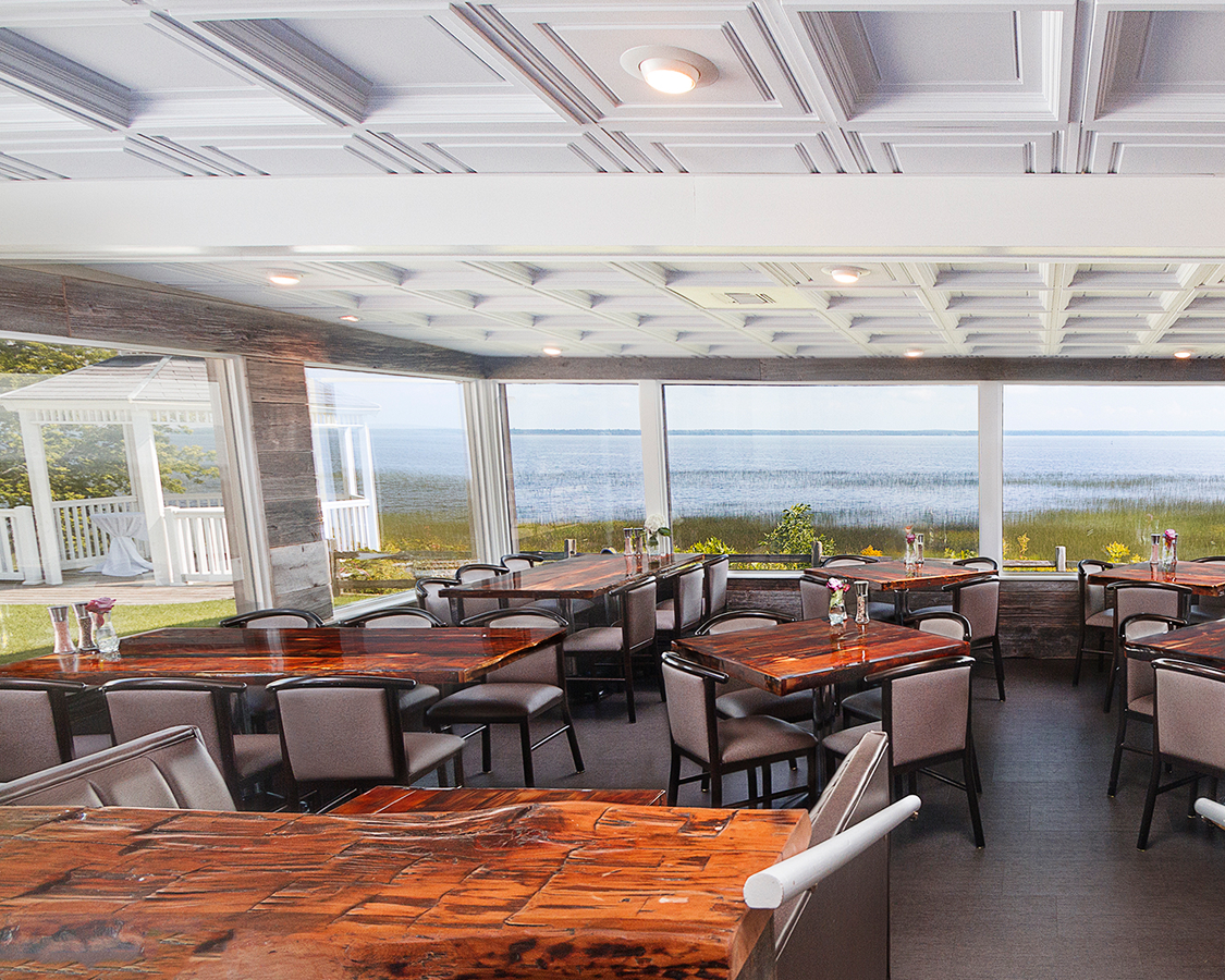 a room with tables and chairs and a view of the ocean