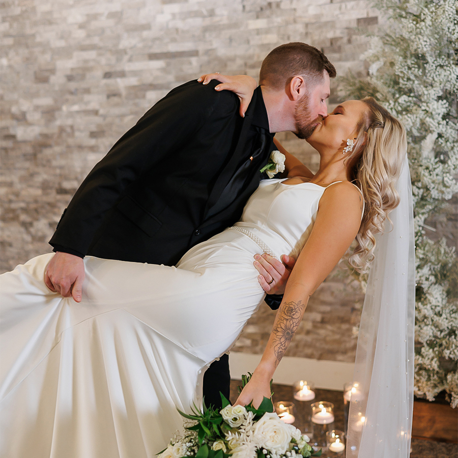 a man and woman kissing in front of a brick wall