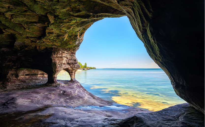 a cave with a view of the water from the beach