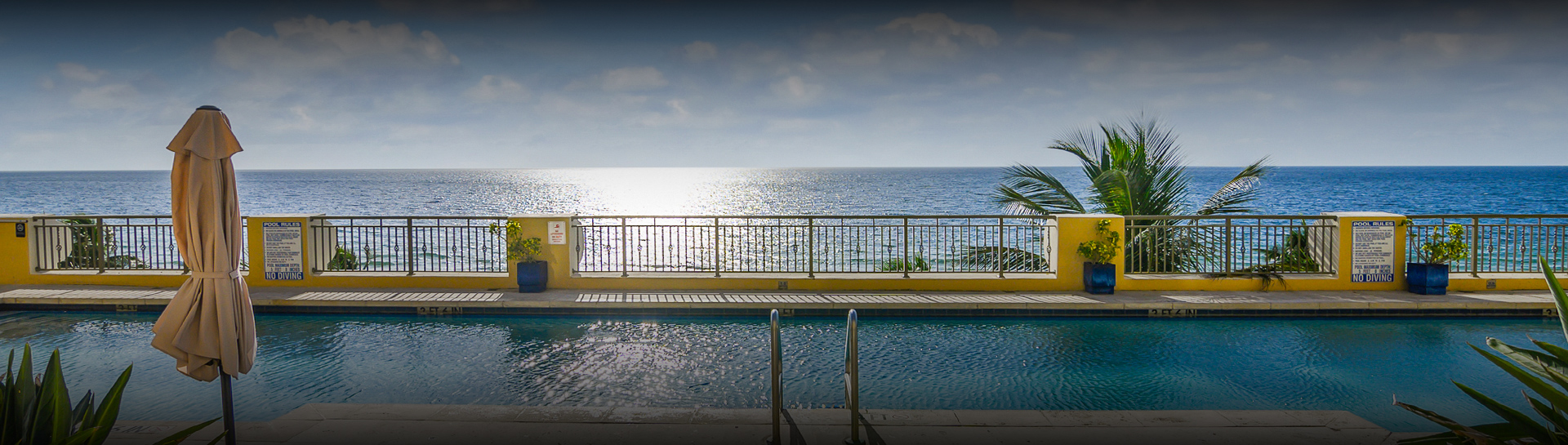 a pool with a railing overlooking the ocean