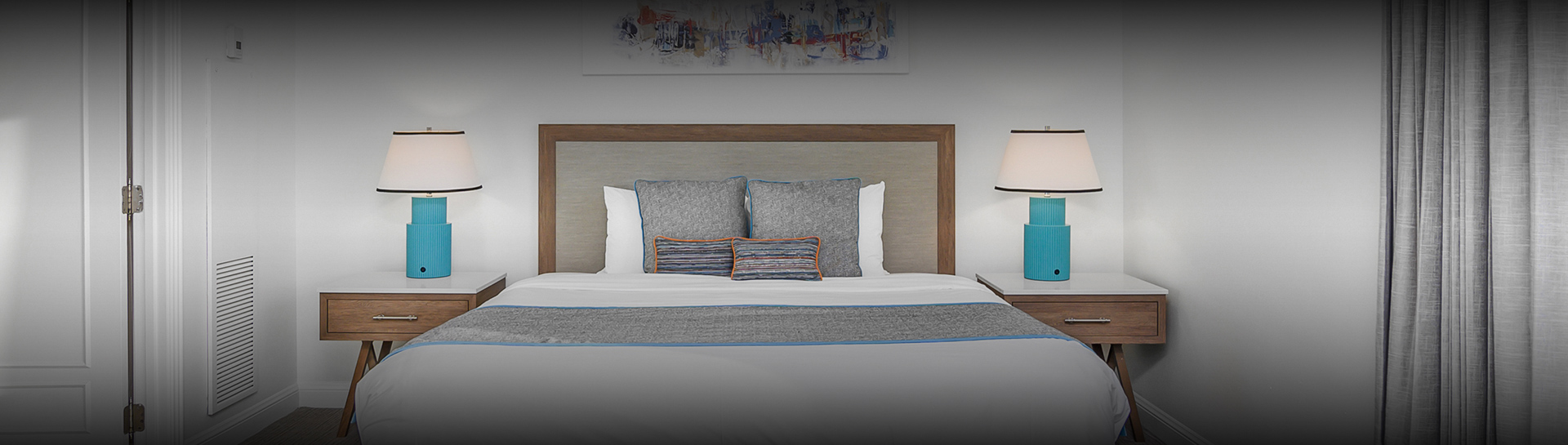 a bed with a lamp and a painting on the wall