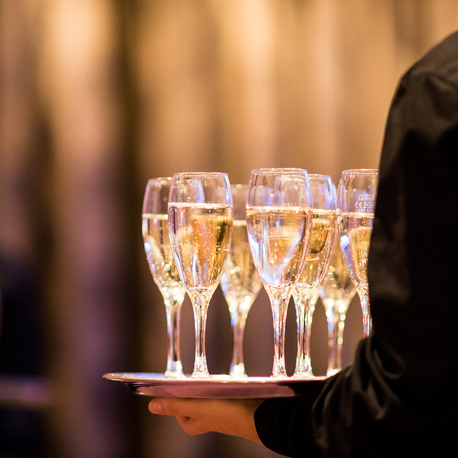 a person holding a tray of champagne glasses