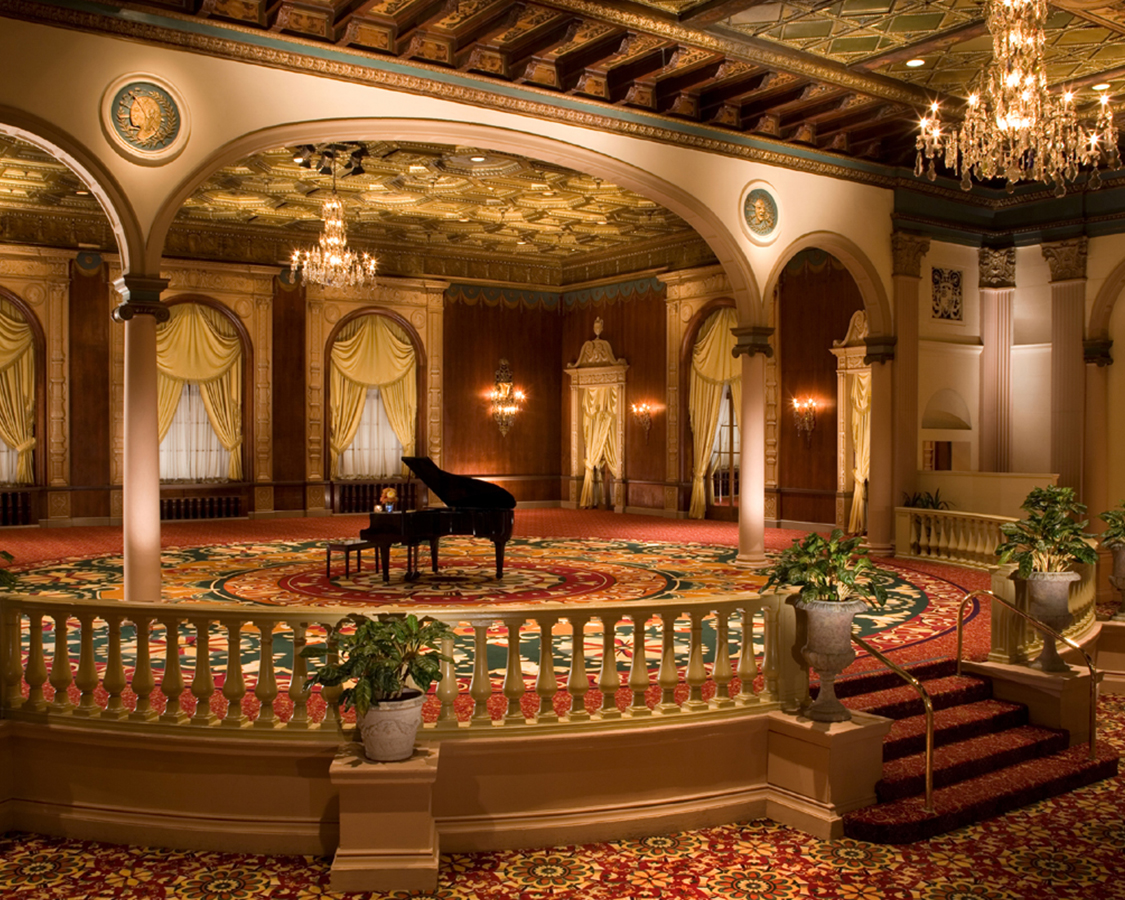 a large room with a piano and chandeliers