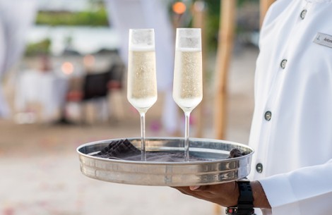 a person holding a tray with champagne glasses