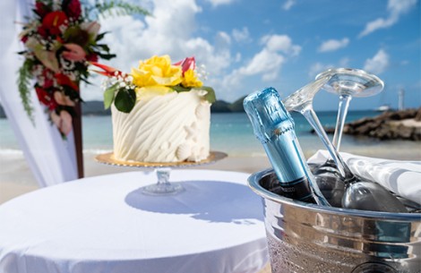 a champagne bottle in a bucket on a table with a cake on the beach