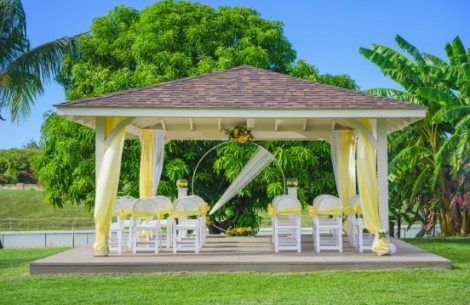 a white and yellow gazebo with chairs and yellow flowers