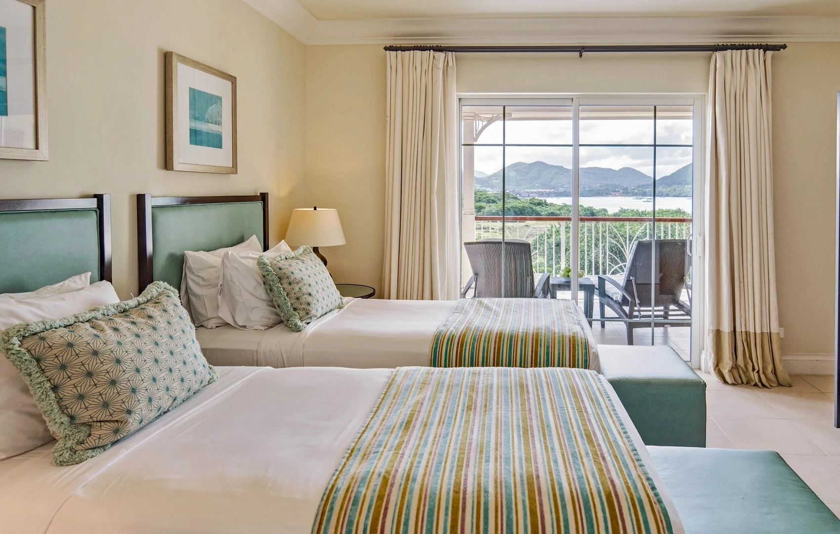 two beds in a room with a balcony overlooking a lake