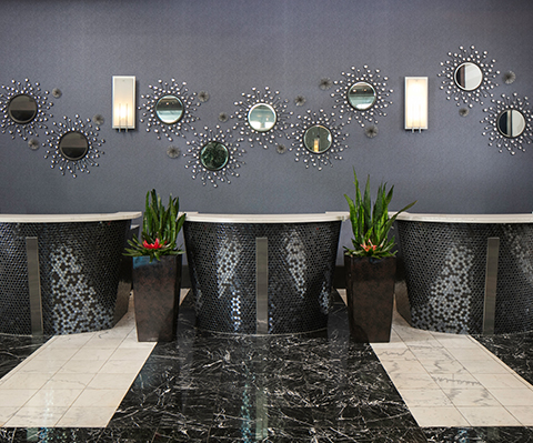 a group of black and white tables with plants in front of a wall