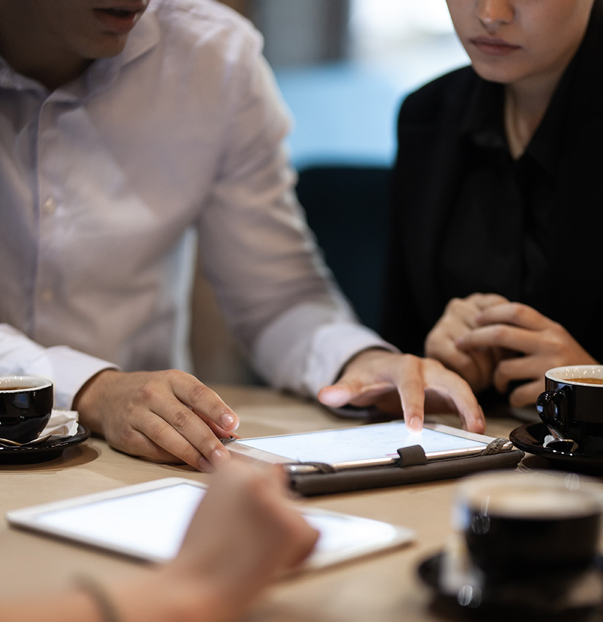 a group of people sitting at a table looking at a tablet