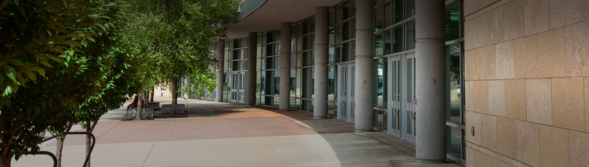 a building with glass windows and a sidewalk